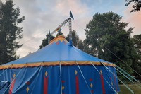 Ein Blaues Zirkuszelt von außen, mit eigener Flagge und Queer Flagge. 1cb089c7717c6bebf40d5725f470514891bdf40d