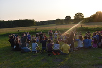 Eine Gruppe Kinder sitzt auf einer Wiese und spielen gemeinsam ein Spiel. 490389787433222b8ce4c42c065db20f8a28e938