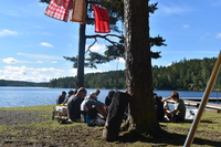 EineGruppte jugendlicher sitzen an einem See und Picknicken zusammen. 1edd1fd28162f7c42d116d45d8e8536a89228046