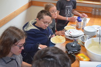 Jugendliche und Teamer*innen backen Waffeln. A4da9d24f5d40e4627ceb47cd1d32cd763e1bf6f