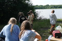 Eine Gruppe Jugendlicher sitzen und Stehen in der Natur. Neben ihnen sind versorgungskisten. D5d15bba3cd6810eb7c8b31293c56e5cc14d009b