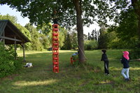 Ein Kind steht auf dem Fertig gebauten Turm aus Flaschenkisten, während er von den anderen Kinder mit einem Seil abgesichert ist 1eac36ebb987e421cdaad60344785e686b2c61c5